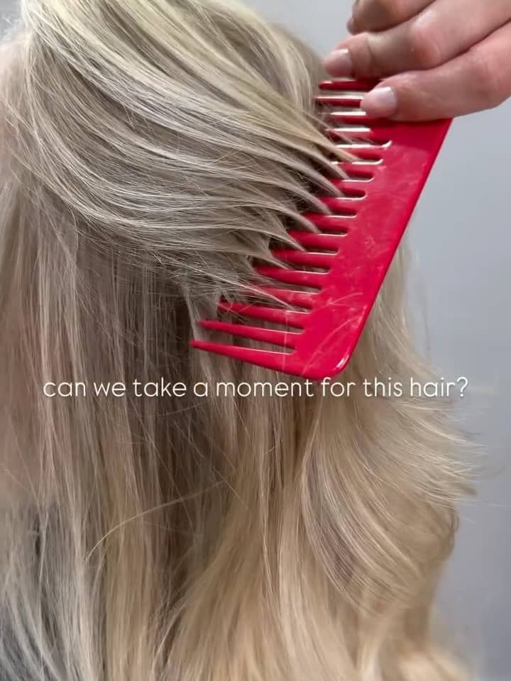 Close-up of clean bright blonde hair being sectioned with a red comb